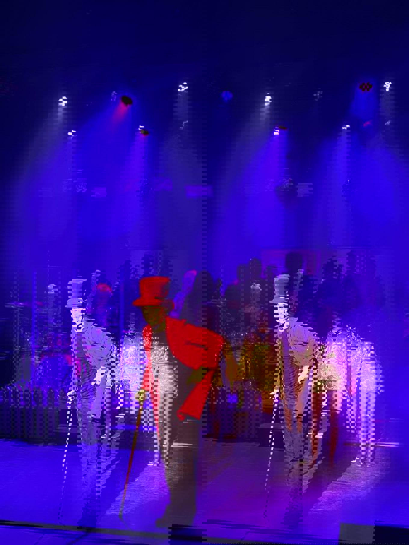 en person med rød hatt og som holder en gitar på en scene